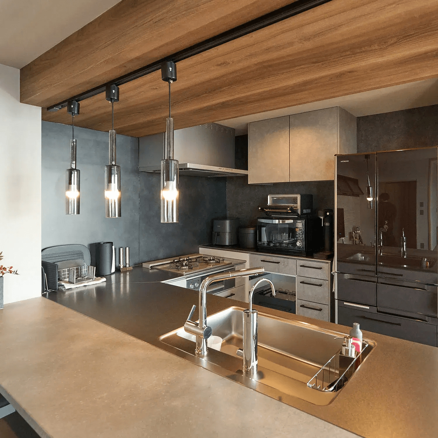 ダークカラーのキッチンとペンダントライトのあるキッチン空間